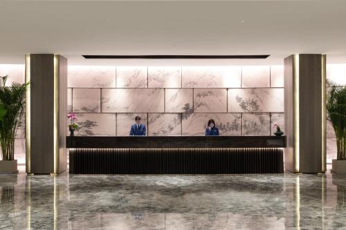 a lobby with two people standing at a reception desk at Holiday Inn Ningde Dijing, an IHG Hotel in Xiapu