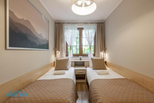 a hotel room with two beds and a window at Apartamenty BlueSky - Przemysłowa in Karpacz