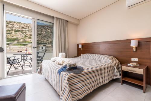 a hotel room with a bed and a balcony at Matala Bay Hotel & Apartments in Matala