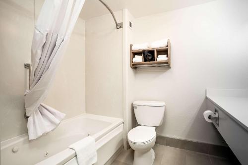 a white bathroom with a toilet and a bath tub at Hawthorn Suites by Wyndham-Oakland/Alameda in Alameda
