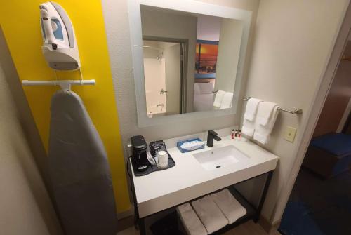 La salle de bains est pourvue d'un lavabo blanc et d'un miroir. dans l'établissement Days Inn by Wyndham Johnson Creek, à Johnson Creek