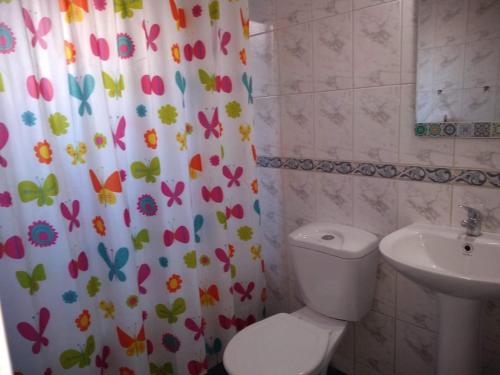 a bathroom with a toilet and a sink and a shower curtain at CABAÑA INTERIOR VILLARRICA in Villarrica