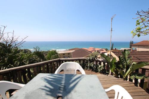 a table and chairs on a deck with a view of the ocean at Surf and Sand - Breakerview in Margate
