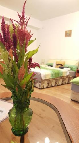 a green vase with purple flowers sitting on a table at Bajusz Vendégház in Tornyosnémeti