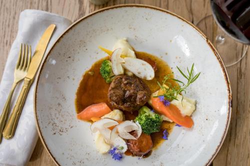 un plato de comida con carne y verduras en una mesa en Hotel und Alpen Apartments mit Sauna - Bürglhöh, en Bischofshofen