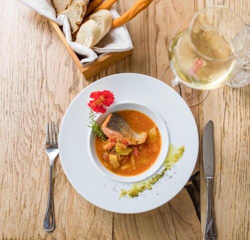 a bowl of soup and a glass of wine and bread at Hotel und Alpen Apartments mit Sauna - Bürglhöh in Bischofshofen