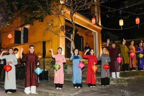 a group of people standing in front of a building with lanterns at Cherry Garden Homestay in Hoi An