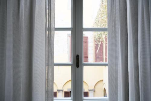 a close up of a window with white curtains at Palazzo Albricci Peregrini in Como