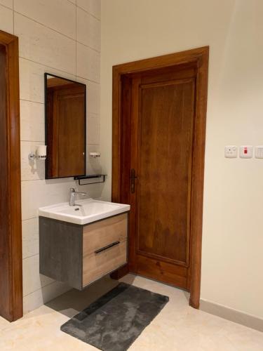 a bathroom with a sink and a wooden door at Luxury fully furnished villa ڤيلا مؤثثة in AlUla
