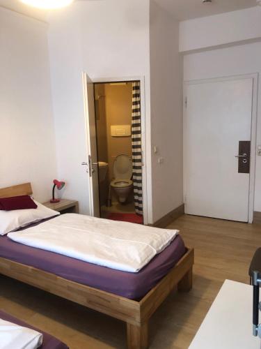 a bedroom with a bed and a bathroom with a toilet at Hotel Pension Schmellergarten in Munich