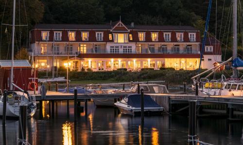 ein großes Gebäude mit vor einem Jachthafen angedockten Booten in der Unterkunft Hotel Wassersleben in Flensburg