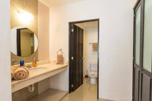 a bathroom with a sink and a mirror and a toilet at Poolside tranquil apartment in Playa del Carmen in Playa del Carmen