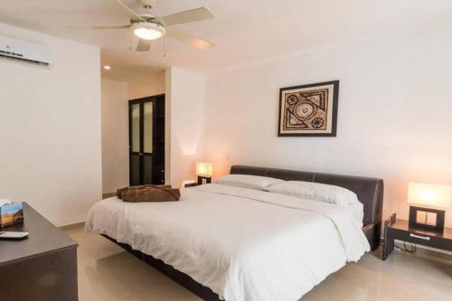 a bedroom with a large white bed with a ceiling fan at Poolside tranquil apartment in Playa del Carmen in Playa del Carmen