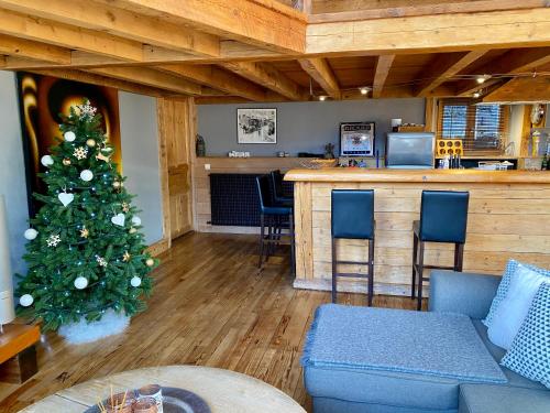 uma sala de estar com uma árvore de Natal e um bar em Ancienne école du Mont em Servoz