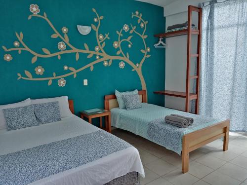 a bedroom with two beds and a tree mural on the wall at Casa Del Aire in Mérida