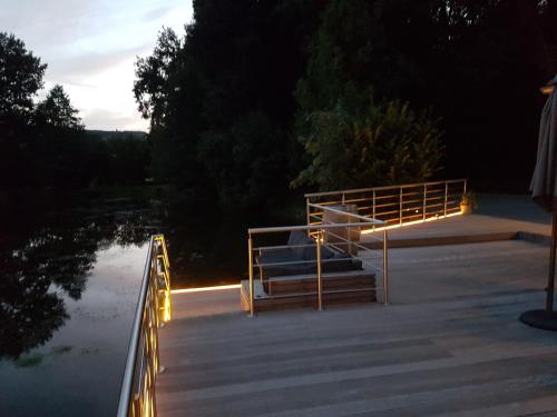 a deck with lights on the water at night at Les étangs du Thioux B&B in Malmedy