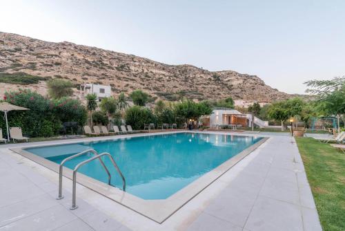 a swimming pool with a mountain in the background at Matala Bay Hotel in Matala