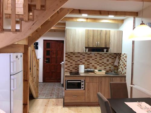 eine Küche mit Holzschränken und einem weißen Kühlschrank in der Unterkunft Apartmani Sredojevic in Kaludjerske Bare