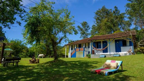 a house with a tree and a chair in the grass at Hotel Fazenda Pedra Grande in Visconde De Maua