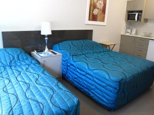 two beds in a hotel room with blue sheets at Strathfield Executive Accommodation in Sydney