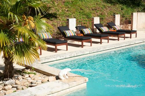 a row of lounge chairs next to a swimming pool at La Bergerie Pradel in Le Beaucet