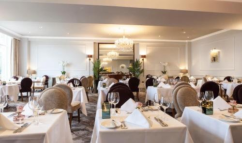 ファルマスにあるThe Royal Duchy Hotelの白いテーブルと椅子、シャンデリアのあるレストラン