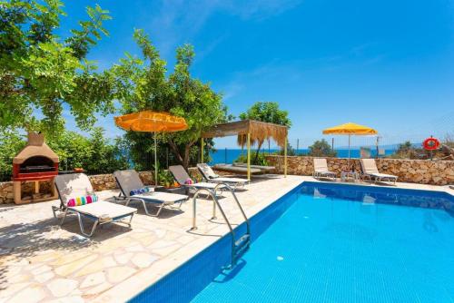 a swimming pool with chairs and umbrellas next to a swimming pool at Astra Villas in Skala Kefalonias