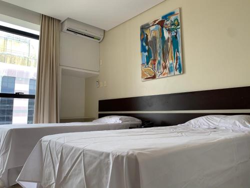 a bedroom with two beds and a painting on the wall at Flat Athenas 1402 in Salvador