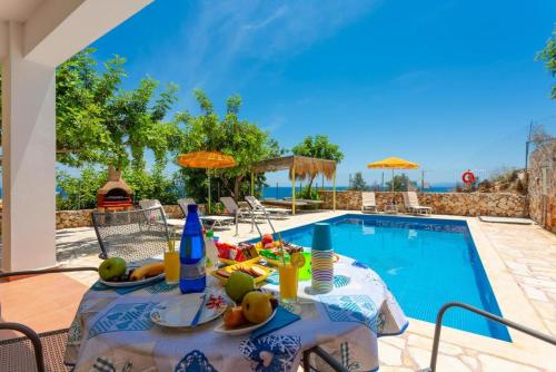 a table with fruit on it next to a swimming pool at Astra Villas in Skala Kefalonias