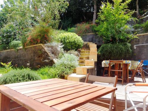 - un jardin avec une table en bois, des chaises et des escaliers dans l'établissement Baglio Antico Forno, à Ustica