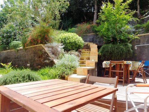 un jardín con una mesa de madera, sillas y escaleras en Baglio Antico Forno, en Ustica