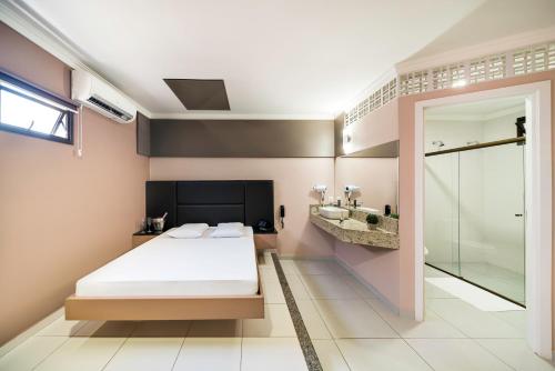 a bedroom with a bed and a walk in shower at Savanas Motel in Ponta Grossa