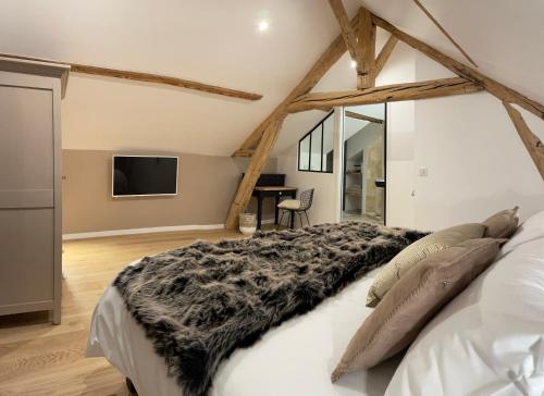 a bedroom with a white bed with a black blanket at L'Atelier des Magnolias in Aumont