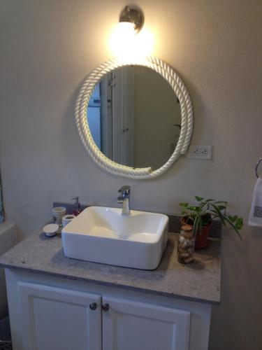a bathroom with a white sink and a mirror at Sea Shells Villa in Christ Church
