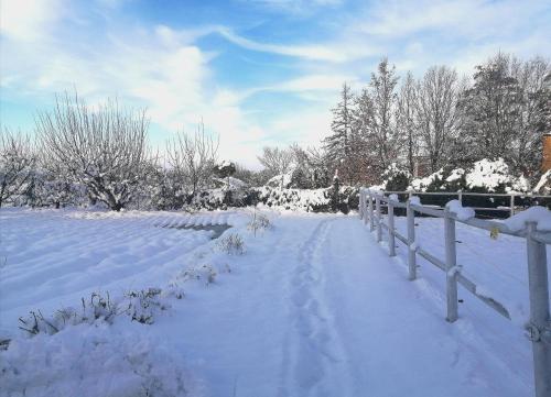 einen schneebedeckten Hof mit einem Zaun und Bäumen in der Unterkunft Felix House in Codevilla