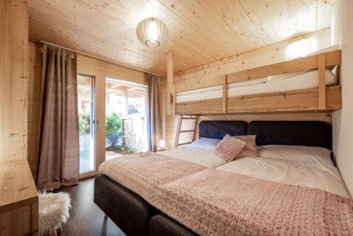 ein Schlafzimmer mit einem Bett in einem Holzzimmer in der Unterkunft Chalet CARVE - Apartments EIGER, MOENCH and JUNGFRAU in Grindelwald