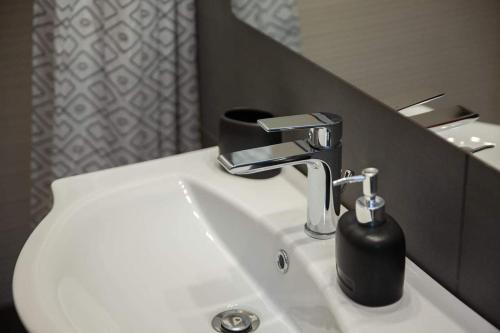 a bathroom sink with a black soap dispenser on it at Etoile apartment in Perissa