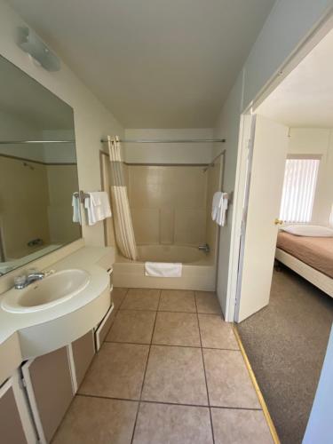 a bathroom with a sink and a shower and a bed at Bristlecone Motel in Big Pine