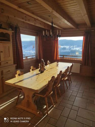 Cette chambre comprend une grande table en bois et des fenêtres. dans l'établissement Les Genévriers, à Foncine-le-Haut