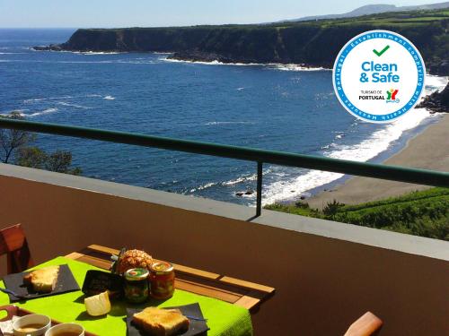 a table on a balcony with a view of a beach at Hilltop Azores - Beach & Countryside in Porto Formoso