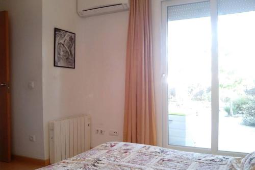 een slaapkamer met een bed en een groot raam bij Bonito apartamento de 3 hab. con jardín in Roses