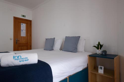 a bedroom with a large white bed with blue pillows at InnEsposende Sports Hostel in Esposende