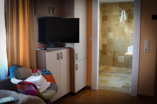 a bathroom with a tv and a crib and a shower at Pensiunea La Rogo in Vulcan