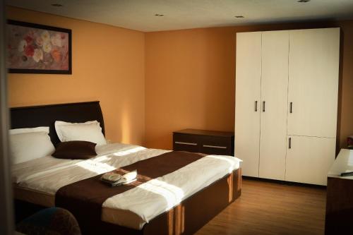 a bedroom with a large bed and a white cabinet at Pensiunea La Rogo in Vulcan