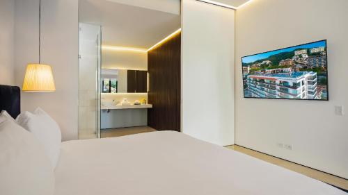 a bedroom with a white bed and a tv on a wall at PIER 57 - 211 Luxurious & Modern 1 BR Romantic Zone in Puerto Vallarta