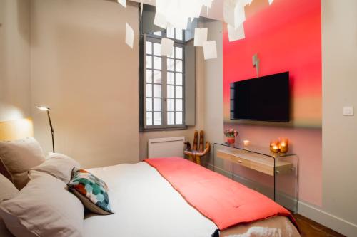 ein Schlafzimmer mit einem Bett und einem TV an der Wand in der Unterkunft room five - parking, balnéothérapie, place nationale, un havre de paix in Montauban