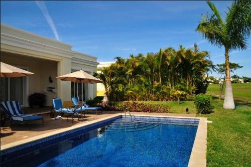 a swimming pool with chairs and umbrellas next to a house at Pueblo Bonito Emerald Luxury Villas & Spa All Inclusive in Mazatlán