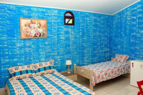 Habitación con 2 camas y paredes azules. en Pousada Beija-flor, en Salinas da Margarida