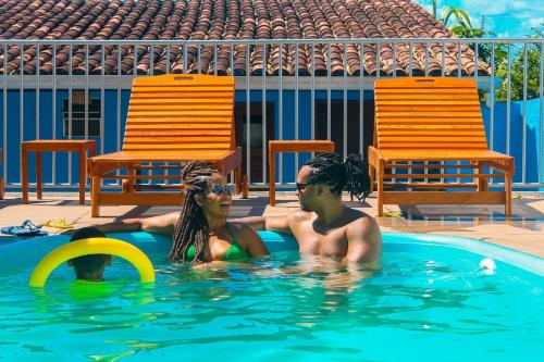 two people in a swimming pool with chairs at Pousada Beija-flor in Salinas da Margarida