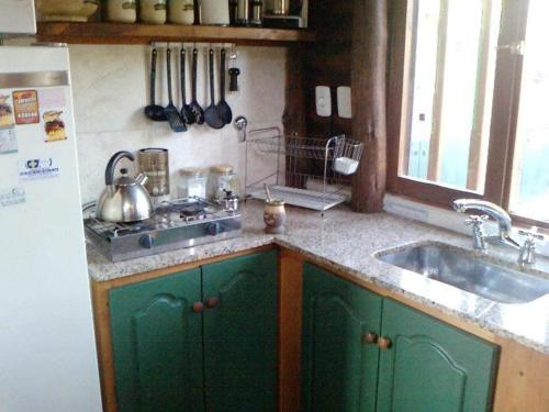 una cocina con armarios verdes y fregadero en LAWIL Cabaña en Tandil
